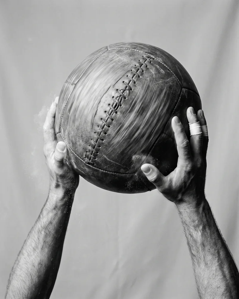 Hands gripping a leather medicine ball caught mid-motion